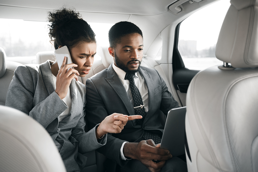 Young afro business couple working in car